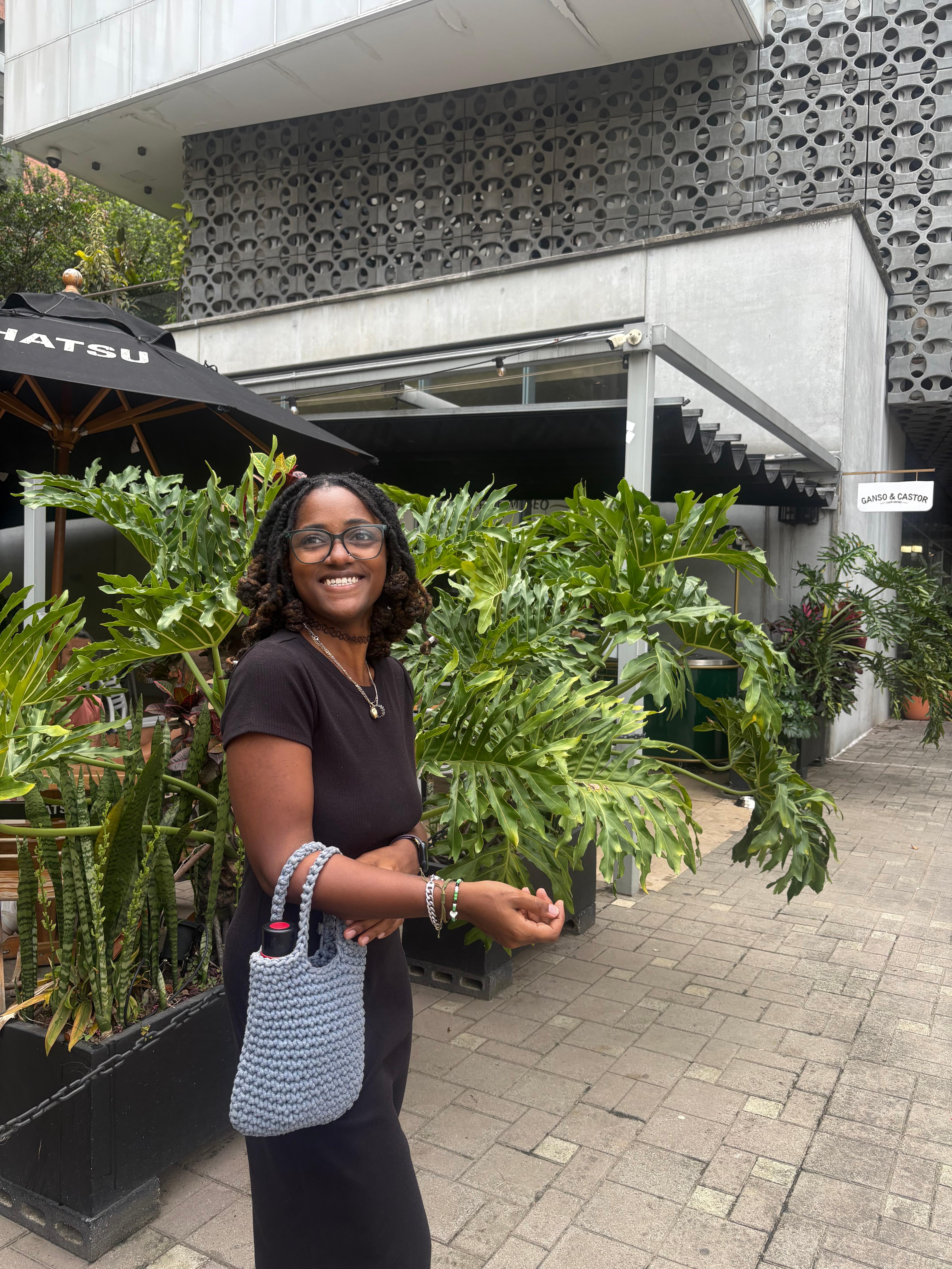 Janelle - Founder of Laura and Vie's Legacy, smiling outdoors in Medellín surrounded by tropical plants