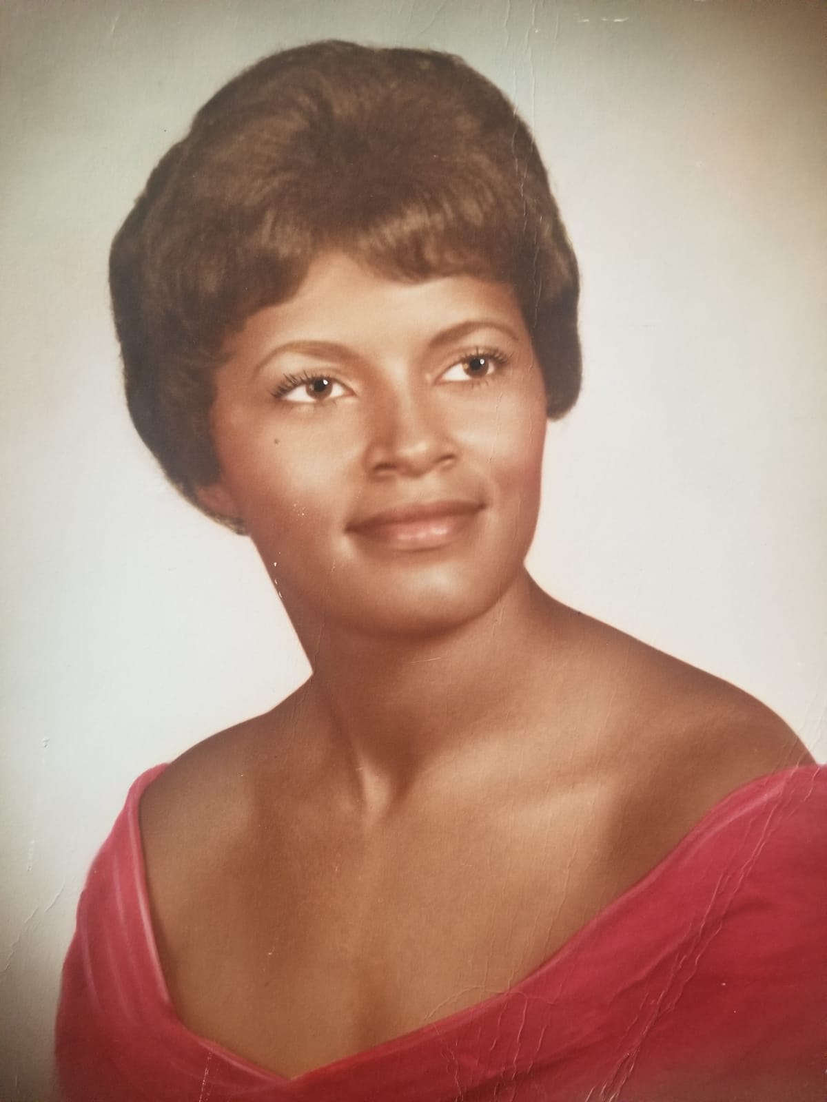 Laura - A vintage portrait photo showing a woman with elegantly styled hair, wearing a red off-shoulder top